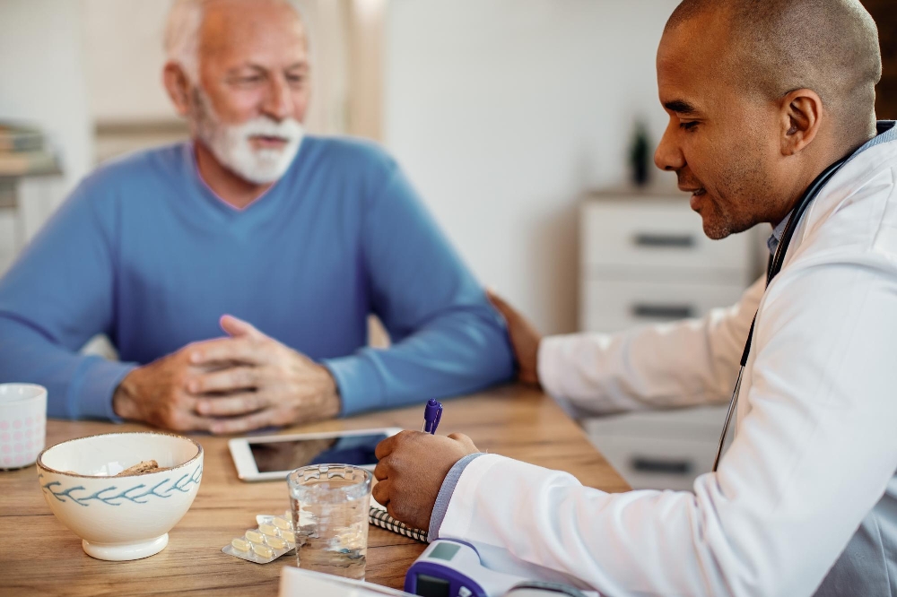 A doctor taking notes while talking with a senior patient in a nursing home.